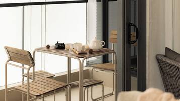 A balcony with a table set for tea, featuring a teapot, cups, and a small decorative item.