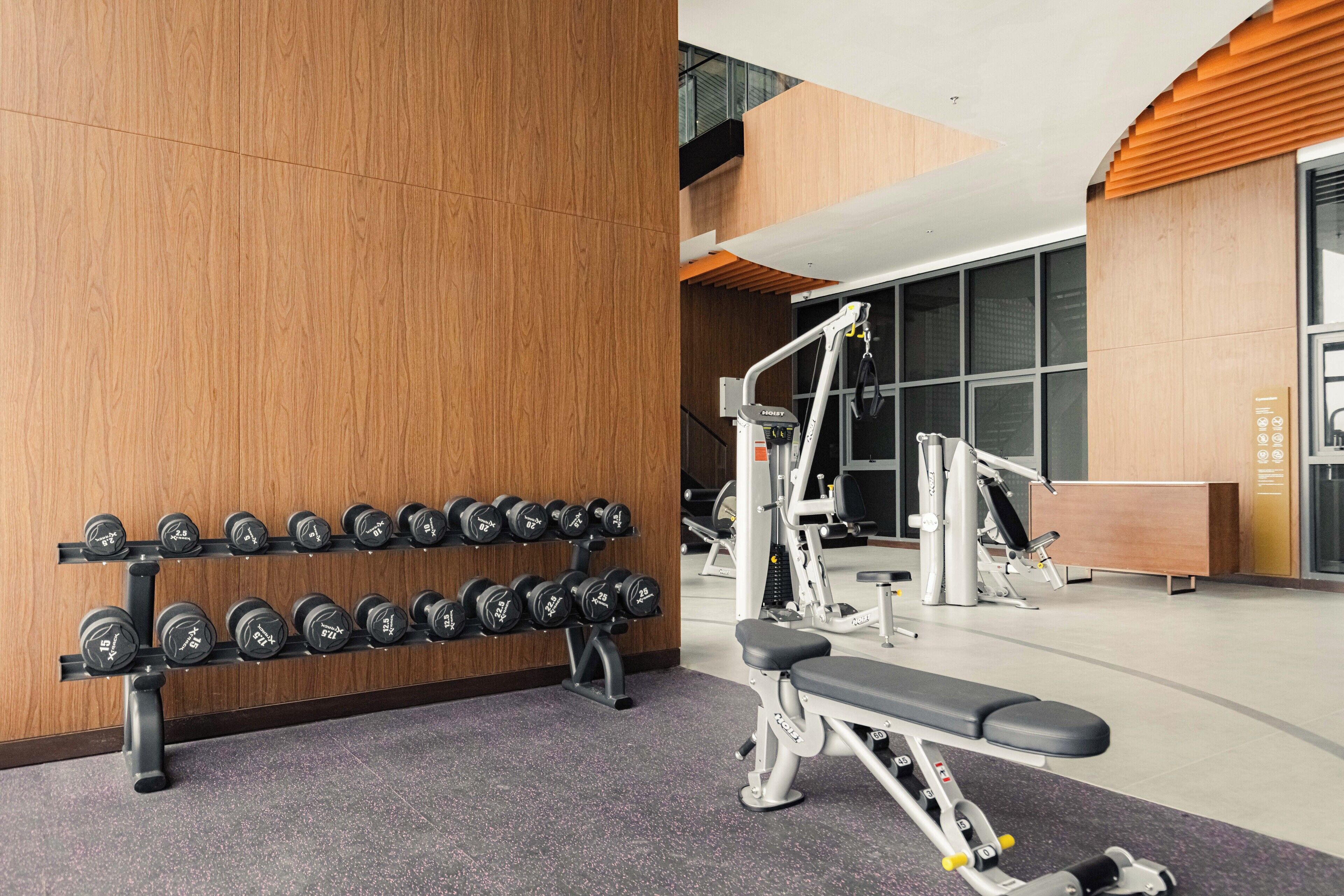 A gym with a bench press, dumbbells on racks, and various exercise machines.