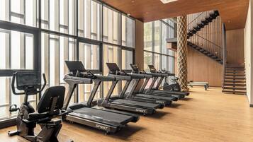 A gym with multiple treadmills, exercise bikes, and a staircase.