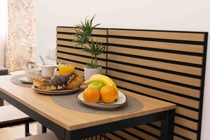 A breakfast table with a croissant, orange juice, a banana, and oranges.