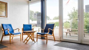 A room with three blue chairs and a small table, large windows, and a view of the outside. - 5 Star Holiday Home in Nexo (Nexø)