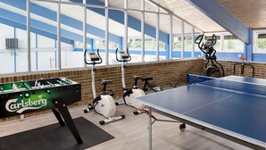 A gym with exercise equipment, a foosball table, and a ping pong table. - 5 Star Holiday Home in Nexo (Nexø)