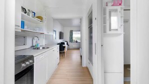 A narrow, white-walled kitchen with wooden flooring, a built-in oven, and a sink. - 5 Star Holiday Home in Nexo (Nexø)