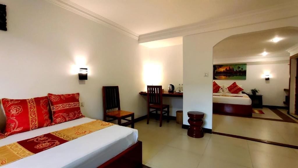 A hotel room with a bed, a desk, and a chair. There is a painting on the wall and a window.