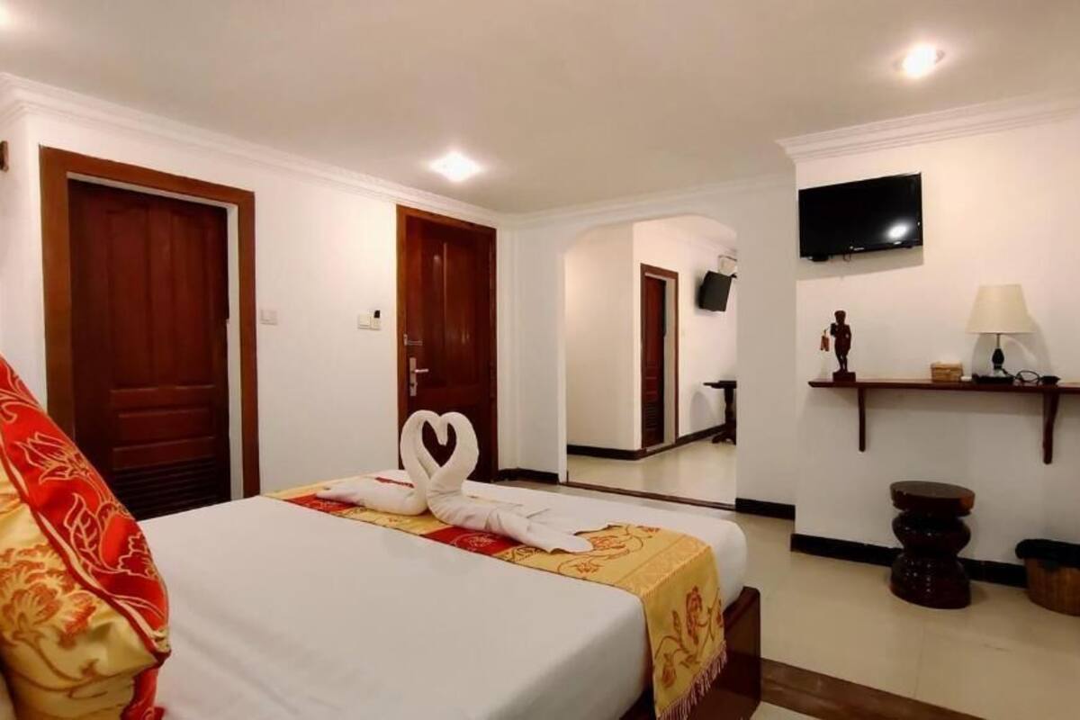 Una habitación de hotel con una cama, un televisor, un espejo y una mesita con una lámpara.