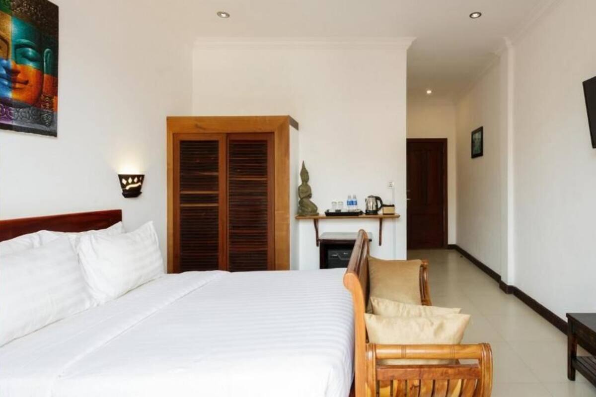 Habitación de hotel con cama, muebles de madera, televisor y una mesita con frutero.