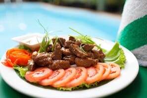 A plate of beef with vegetables and a dipping sauce. - La Villa du Bonheur (Siem Reap)