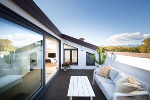A modern rooftop terrace with a white sofa, a white table, and a large cactus plant. - Loft Elisa, with terrace and car place (Lucca)