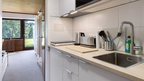 Een moderne keuken met een groot raam, een ingebouwde magnetron, een roestvrijstalen spoelbak en een houten aanrecht.
