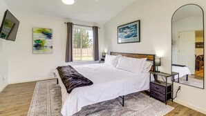 A bedroom with a large bed, a bedside table, a mirror, and artwork on the walls. - Water Views & Hot Tub: 'Kim's Kastle' in Stanwood! (Stanwood)