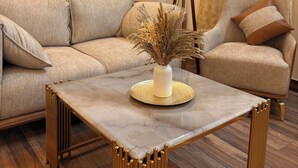 A living room with a beige sofa, a matching armchair, a coffee table with a vase of dried plants, and a floor lamp. - Noble Nook Stay - Bhimtal (Dungsilrawat)