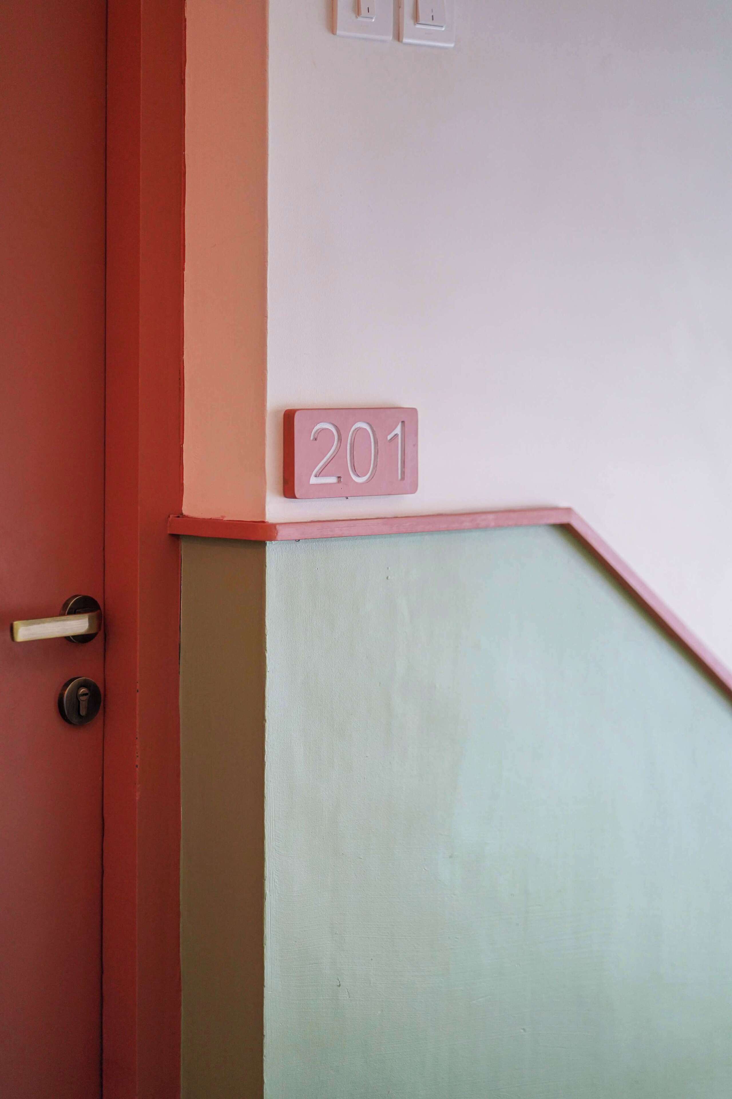 Une porte avec une plaque portant le numéro « 201 » et un interrupteur juste au-dessus.