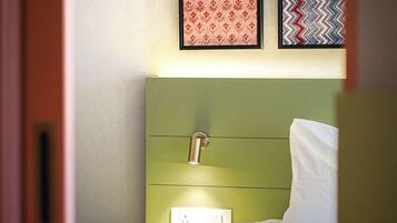 Una habitación de hotel con un cabecero verde, una cama blanca y dos cuadros en la pared.