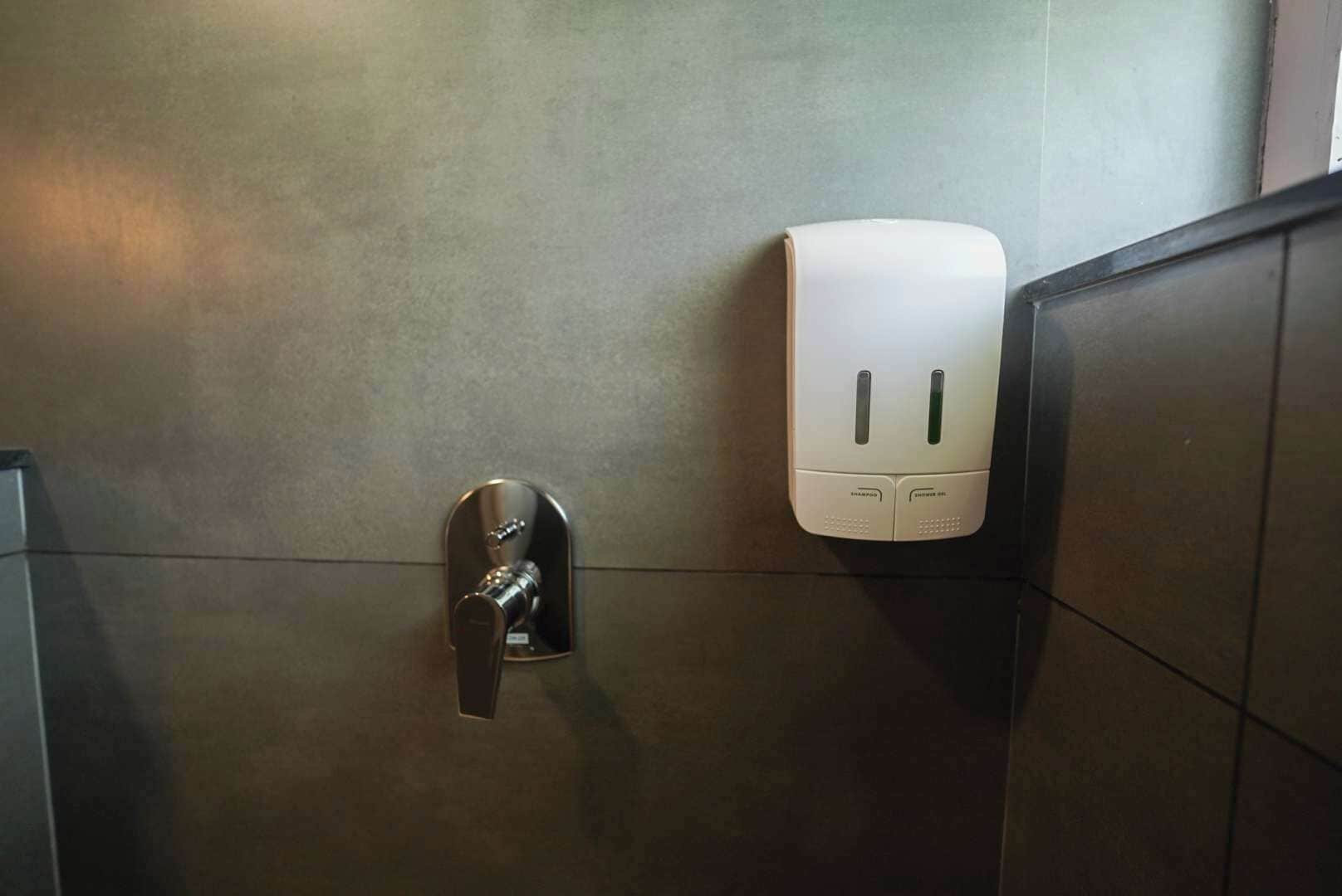 Baño con secamanos y dispensador de toallas de papel en la pared.