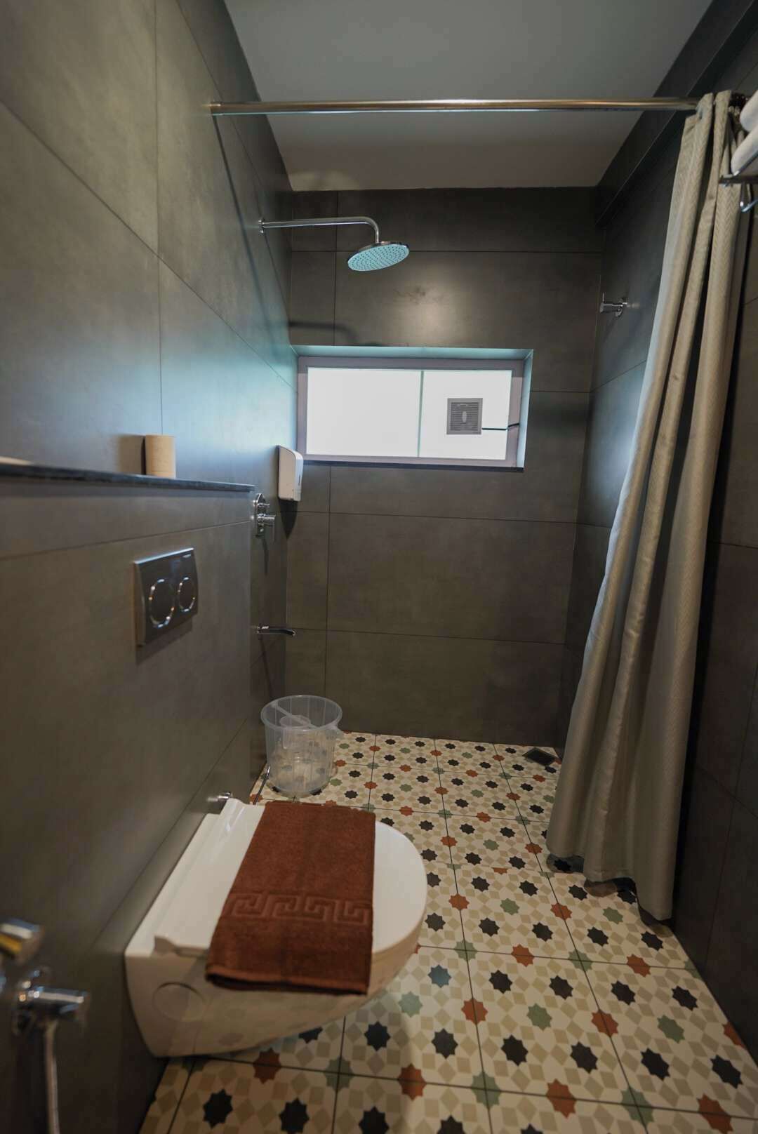 A compact bathroom with a shower, a toilet, and a window.