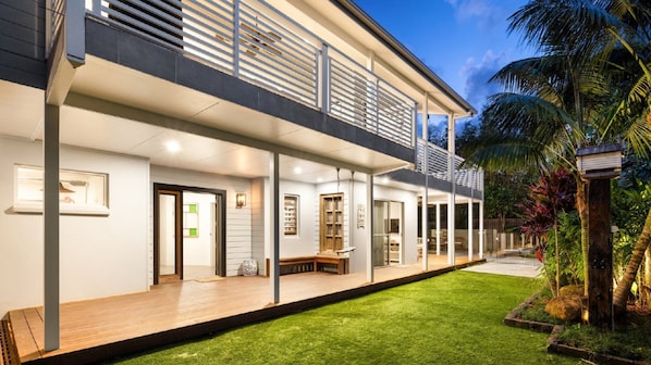 A two-story house with a covered porch, a small deck, and a well-maintained lawn. - The Anchorage - by Lifestyle. Brunswick Heads (NEW BRIGHTON)