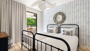 Un dormitorio con cama, ventilador de techo, ventana con cortinas y pared con diseño.