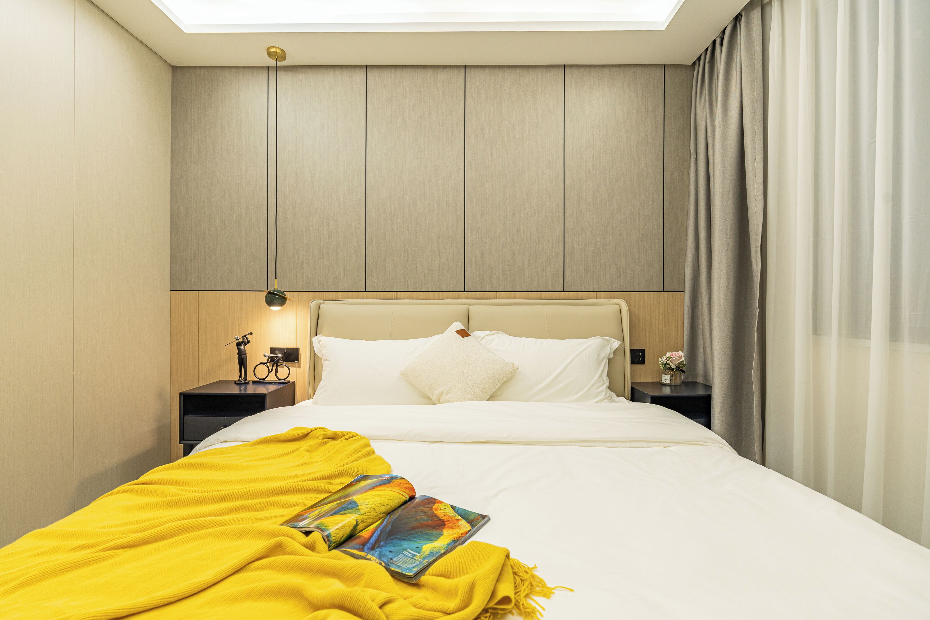 Une chambre d’hôtel moderne avec un grand lit, une lucarne et une table de chevet avec une lampe.