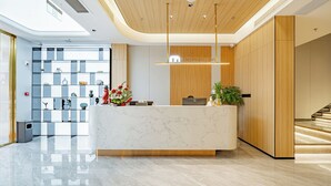 A modern reception area with a marble counter, wooden paneling, and a glass display wall. - Xiangwang Meisu Hotel (Zhuhai)