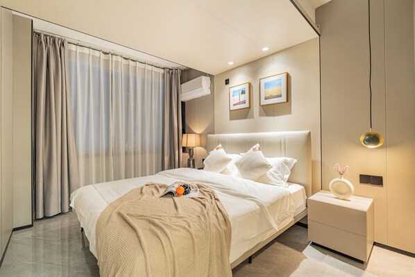 Une chambre d’hôtel moderne avec un grand lit, une table de chevet, une commode et un climatiseur fixé au mur.
