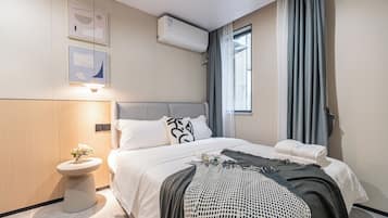 Una habitación de hotel moderna con cama, mesita de noche y ventana con cortinas.