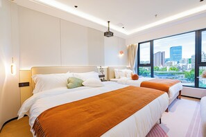 Een hotelkamer met twee bedden, een groot raam met uitzicht op de stad en een plafondprojector.