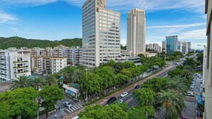 A high-rise building with multiple floors, surrounded by lush green trees and a clear blue sky. - Xiangwang Meisu Hotel (Zhuhai)