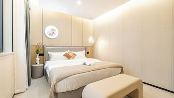 Un dormitorio moderno con una cama grande, mesitas de noche, una lámpara de pared y una pequeña planta en maceta.