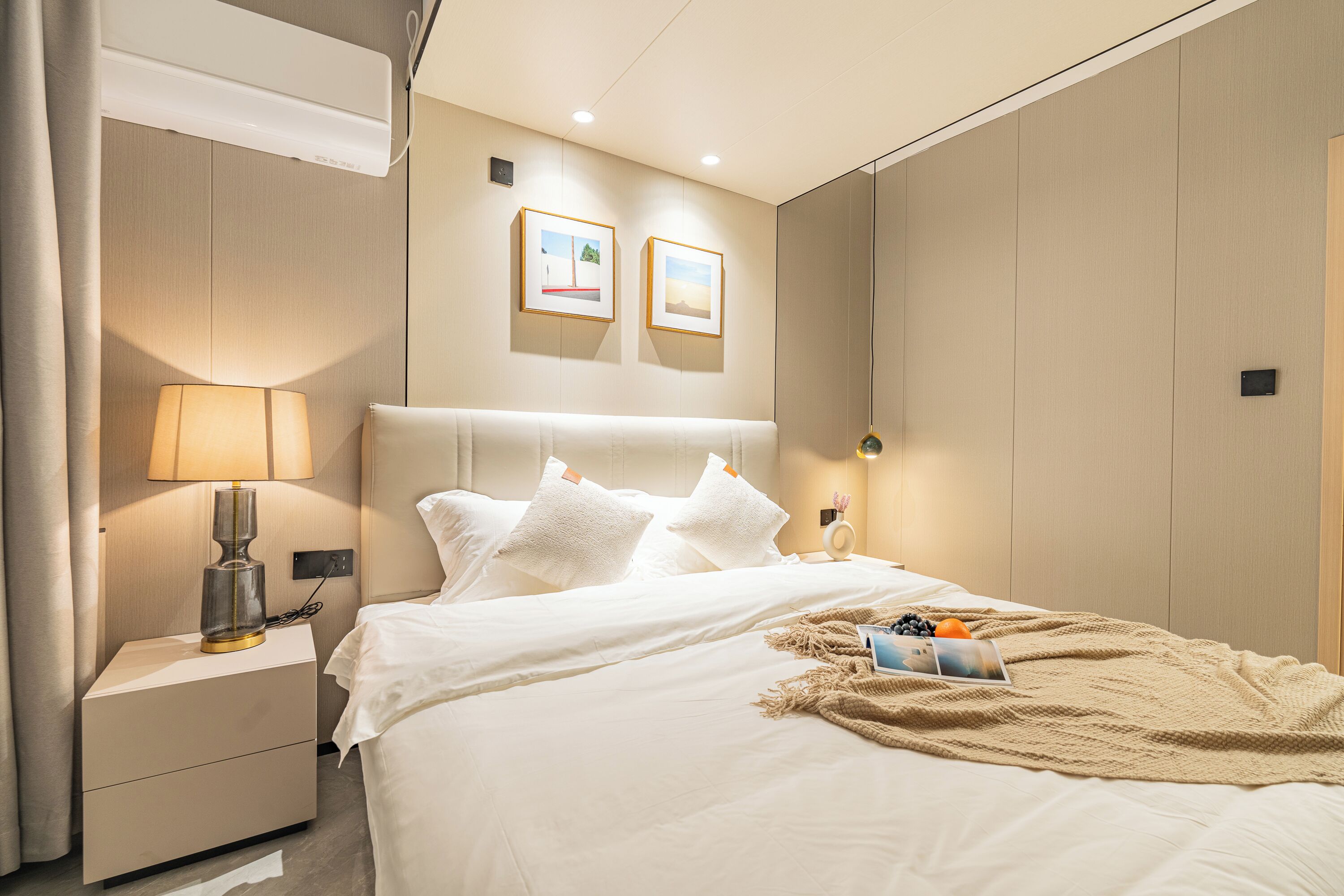 A modern hotel room with a neatly made bed, a bedside lamp, and a small table with a lamp.