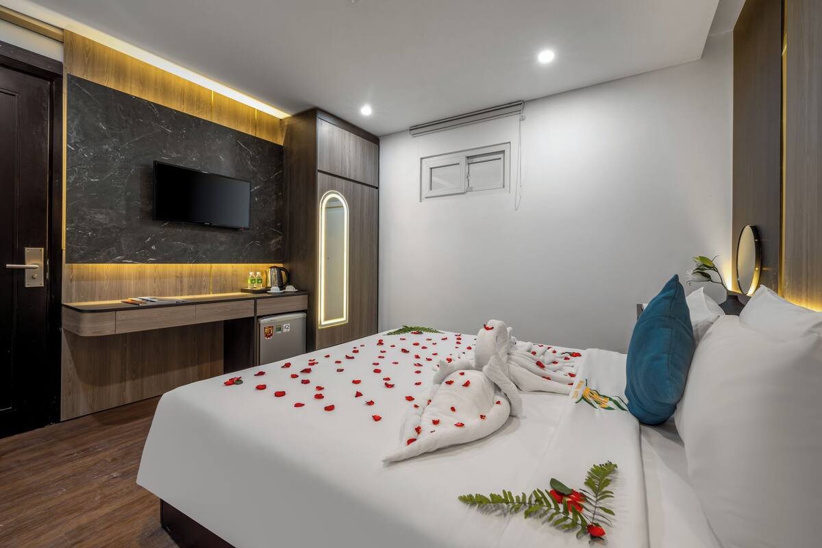 Une chambre d’hôtel avec un lit, un bureau, une télévision et une petite fenêtre.