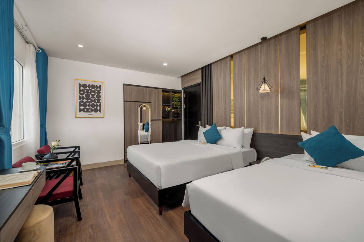 Une chambre d’hôtel moderne avec deux lits, un bureau avec une chaise, une petite table et un miroir.
