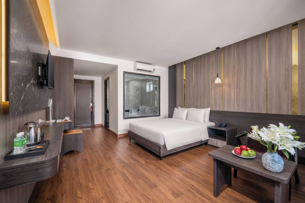 Une chambre d’hôtel moderne équipée d’un lit, d’une table de chevet et d’un petit bureau avec une chaise.