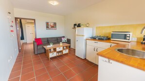 Eine kleine Küche mit Kühlschrank, Mikrowelle und einer Holzausziehtafel.