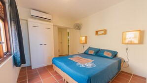 Ein Schlafzimmer mit einem Bett, einem Kleiderschrank, einer Klimaanlage, einem Ventilator und zwei Wandlampen.