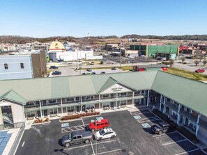 A Colonial Crest Inn & Suites with a parking lot, a red truck, and a green building in the background.