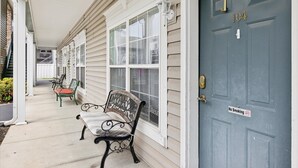 A house with a porch, a blue door with a 'No Smoking' sign, and two benches.