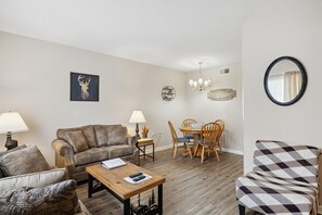 Un salón con sofá, sillón, mesa de centro y mesa de comedor con sillas.