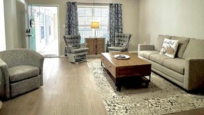 A spacious living room with a large window, a ceiling fan, and a sofa.