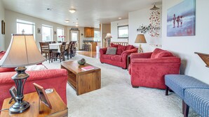 Een ruime woonkamer met rode banken, een houten salontafel en een eethoek, met een keuken op de achtergrond.