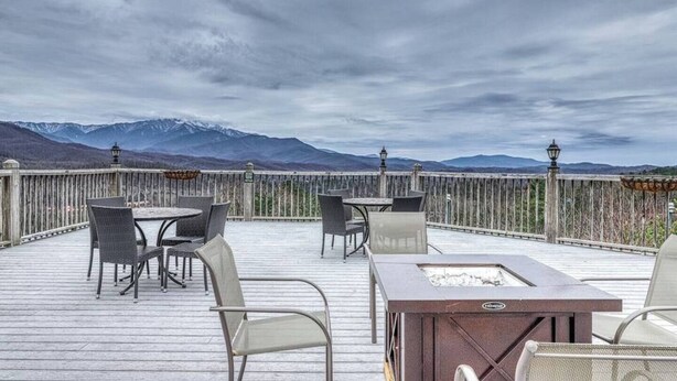 Una terraza con asientos al aire libre y una fogata, con vistas a un paisaje montañoso.
