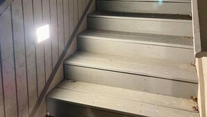 Una escalera de madera con barandilla, que sube a un nivel superior.