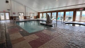 Una piscina interior con varias pistas, una silla de salvavidas y vistas a la ciudad a través de grandes ventanales.