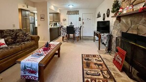 Una sala de estar acogedora con chimenea, comedor y cocina al fondo.