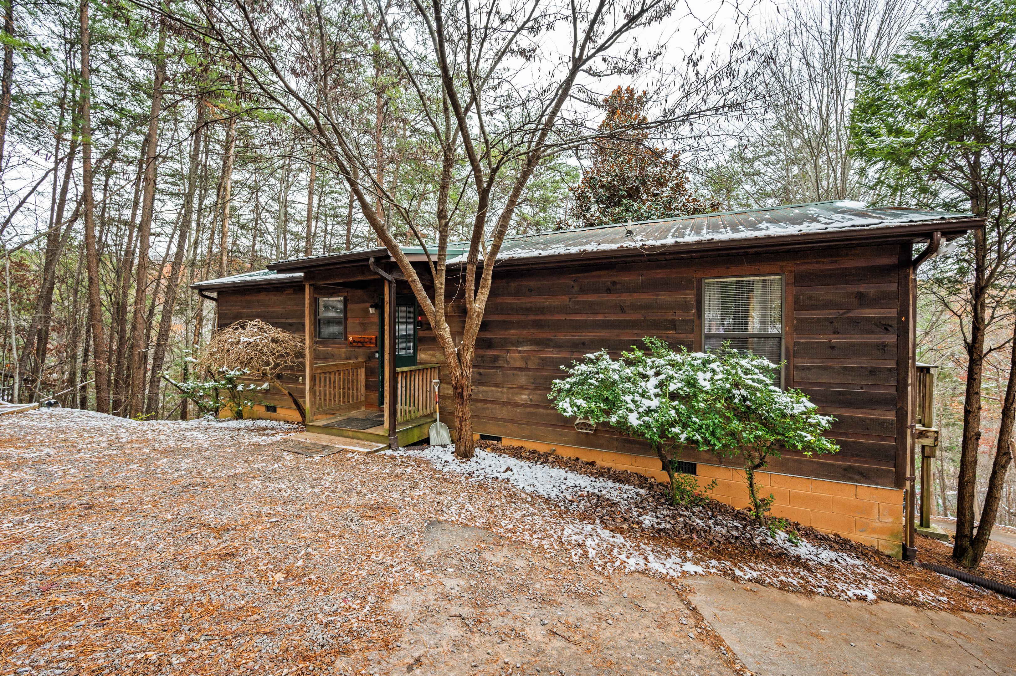 Ein rustikales Holzhaus mit Veranda und einem kleinen Gartenbereich mit schneebedeckter Bepflanzung.