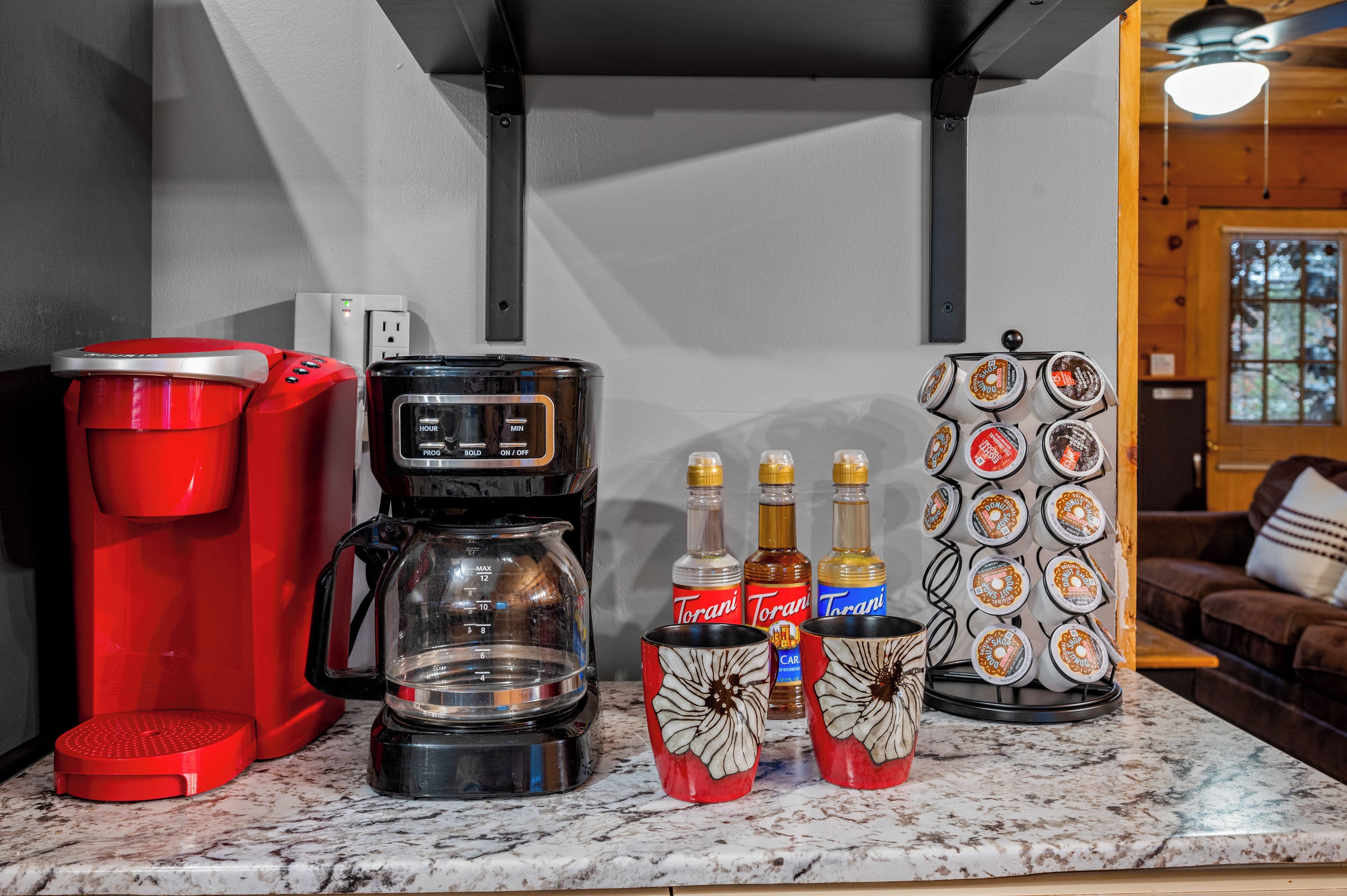 A kitchen counter with a coffee maker, a scale, and Torani syrup bottles.