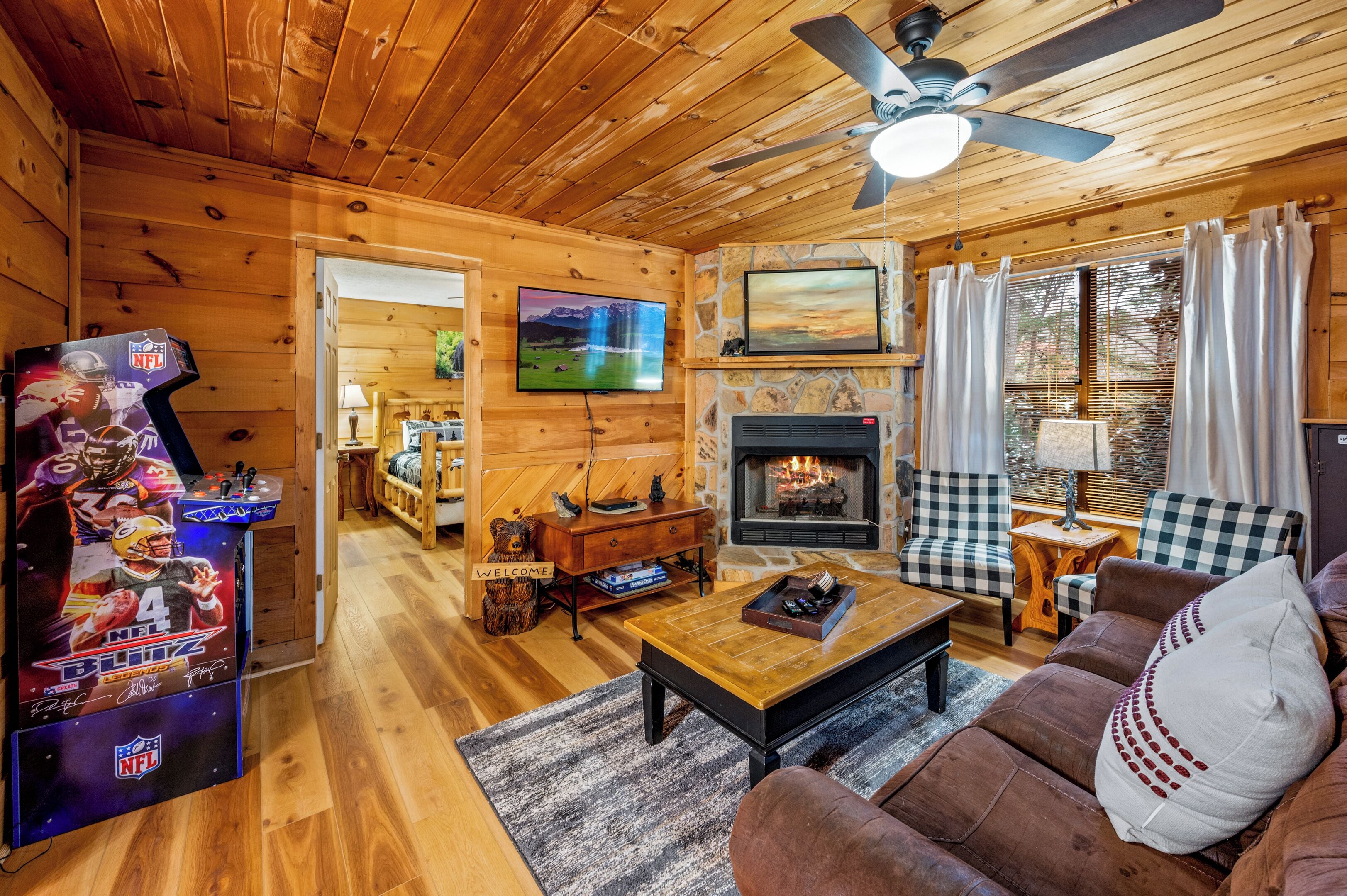 A cozy log cabin interior with a fireplace, a television, and a bear-shaped welcome sign.