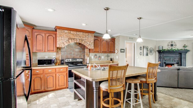 A kitchen with wooden cabinets, a stone arch, a central island, and bar stools. - Quiet Family Home in Headland w/ Games & Yard (Headland)