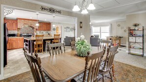 A spacious dining area with a wooden table and chairs, a chandelier, and a kitchen in the background. - Quiet Family Home in Headland w/ Games & Yard (Headland)