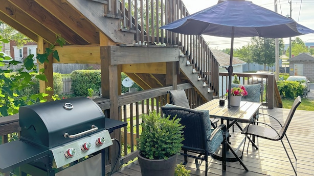 Eine Holzterrasse mit Grill, Gartenmöbeln und einem Blumentopf.