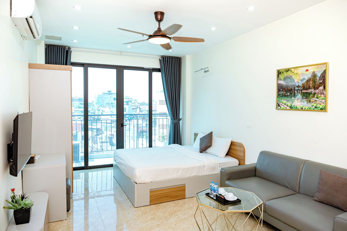 A modern hotel room with a bed, sofa, and a glass coffee table.